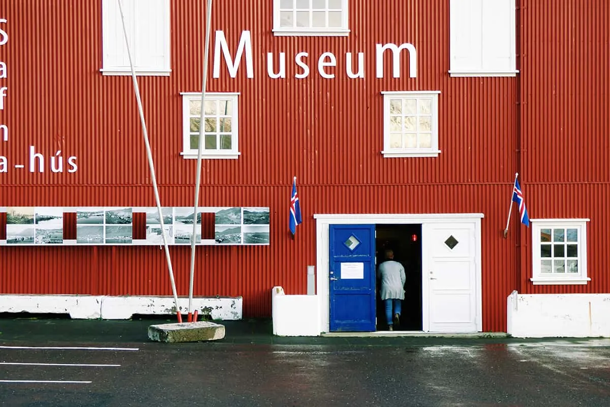Rauða Safnahúsið með hvítum gluggakörmum og blárri útidyrahurð.